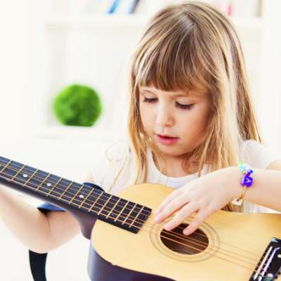 Young girl learning to play guitar in a private guitar lesson