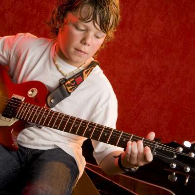 Young boy learning to play guitar in a private 1 on 1 music lesson. 