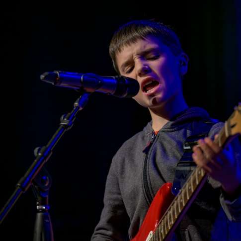 Teenage Singer in a rock bank performing on stage at the Rock and Pop Music Academy.